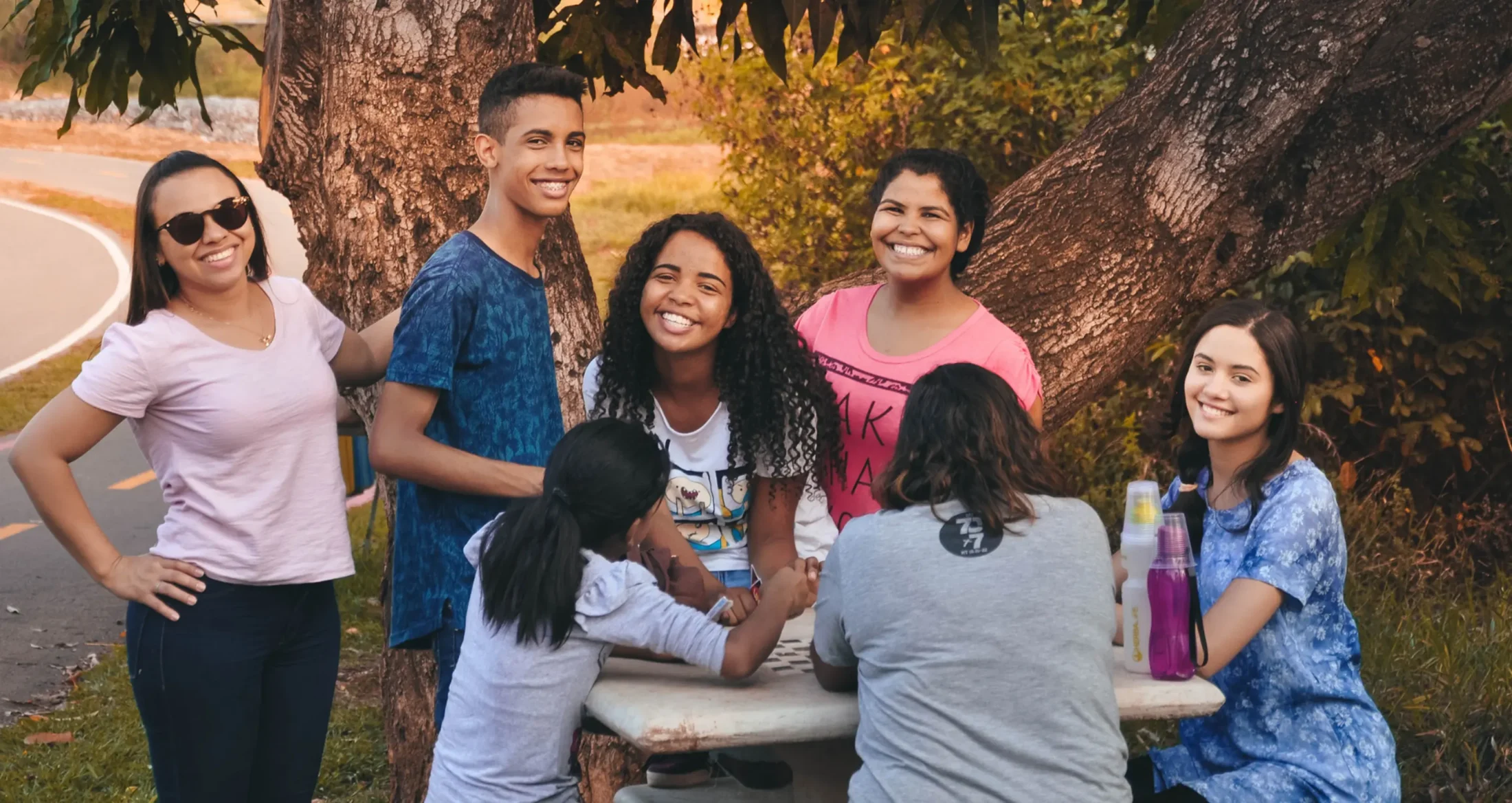 Diverse young people smile together at an outdoor table, supported by Abuse Counseling & Therapy.