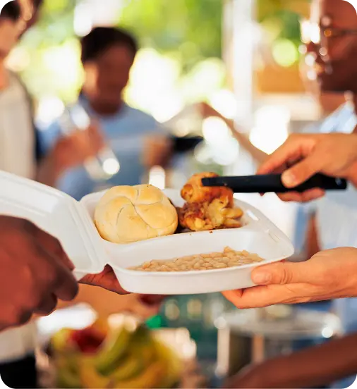 A volunteer serves a warm meal at an Abuse Counseling & Therapy community outreach event.