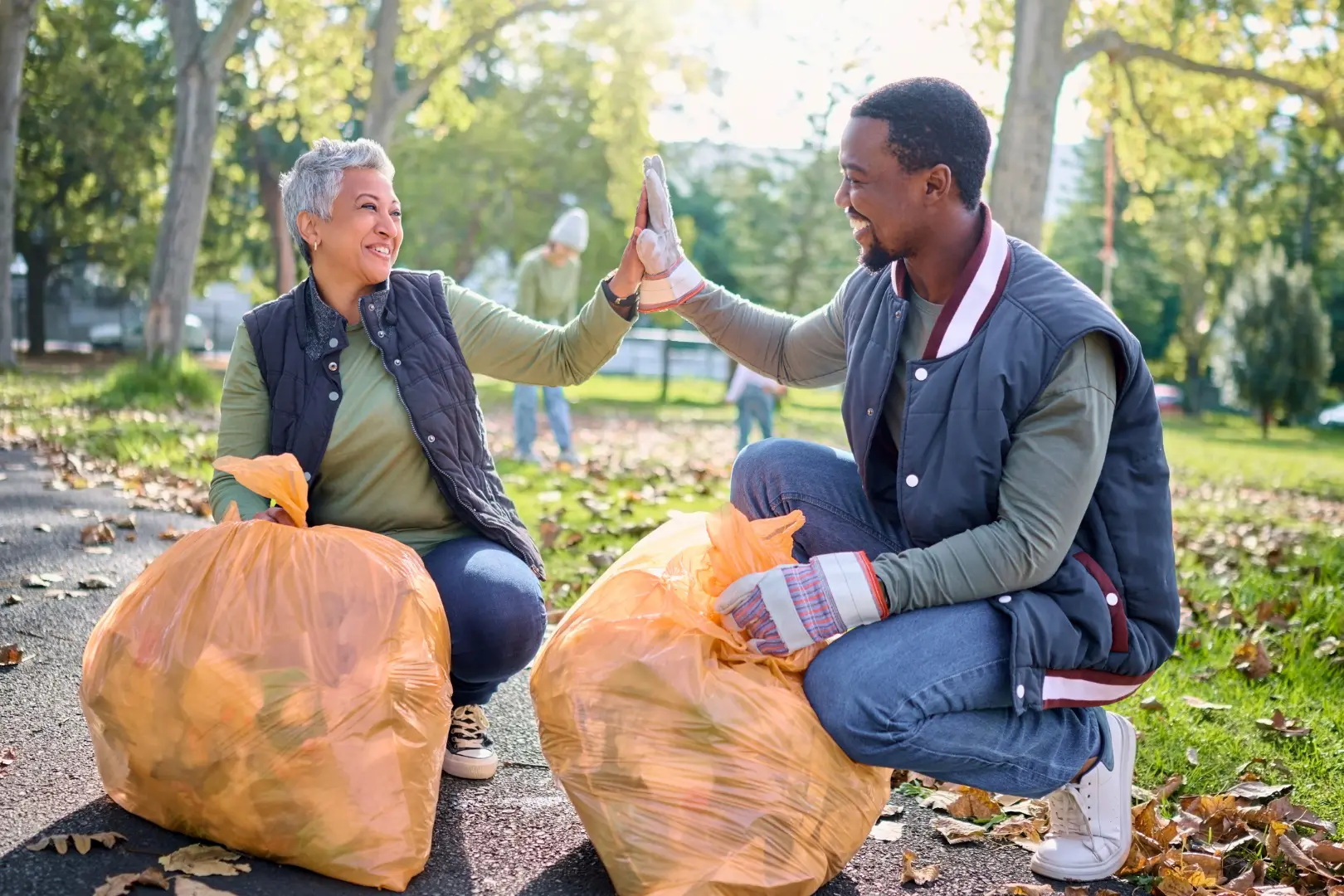 Smiling Abuse Counseling & Therapy volunteers high-five while cleaning up a park.