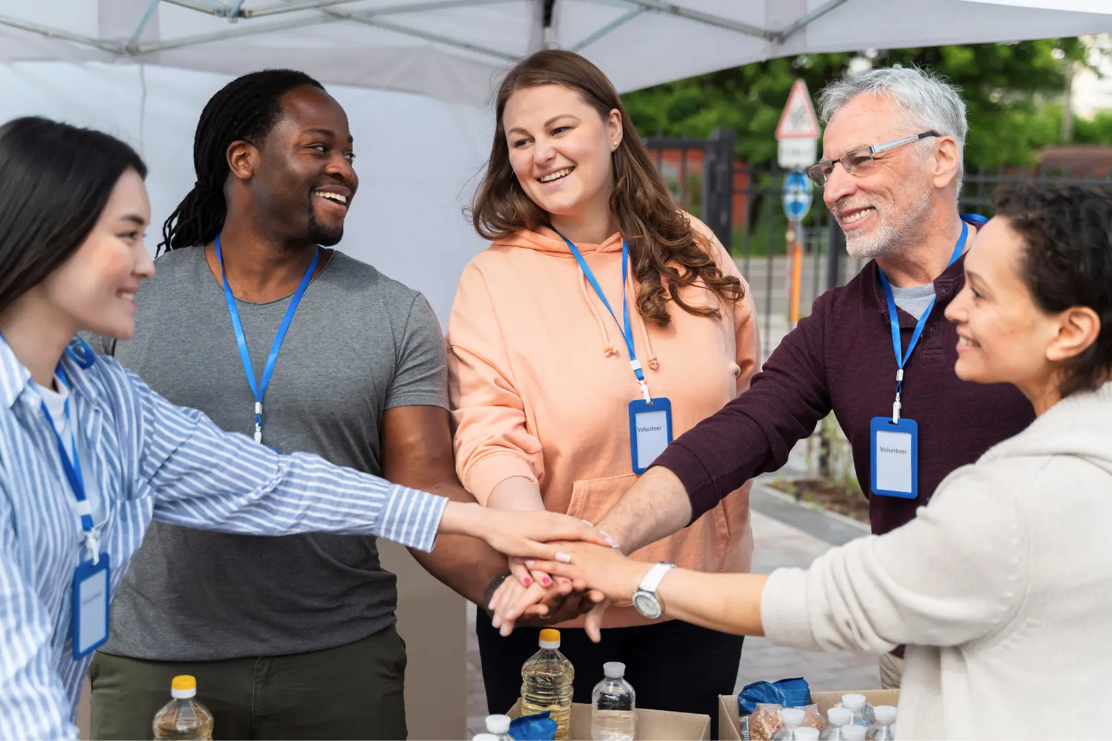 Diverse Abuse Counseling & Therapy volunteers stack hands in solidarity at a community event.