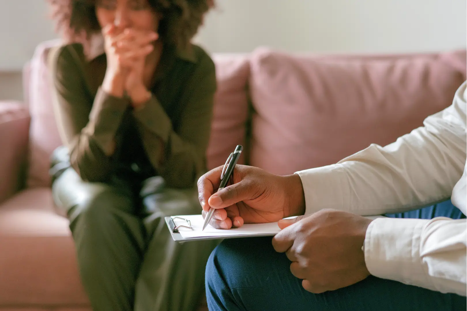A therapist takes notes during an Abuse Counseling & Therapy session with an emotional client.