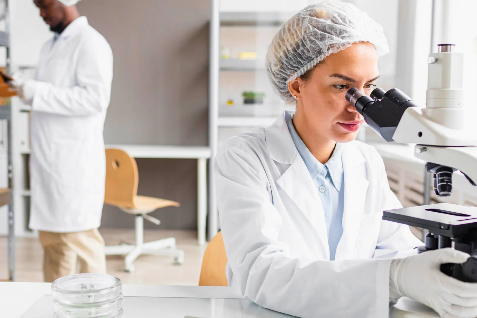 A researcher at Abuse Counseling & Therapy looks through a microscope in a laboratory.