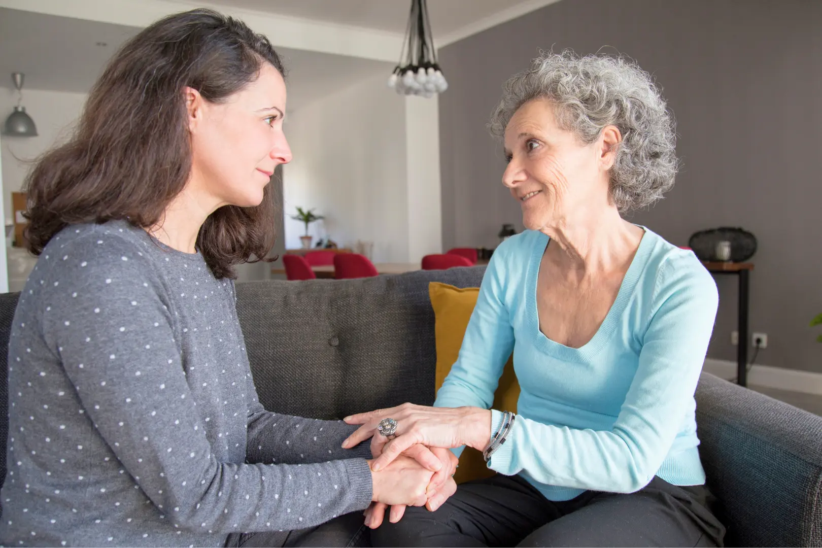 An Abuse Counseling & Therapy counselor holds hands with an older woman to offer support.