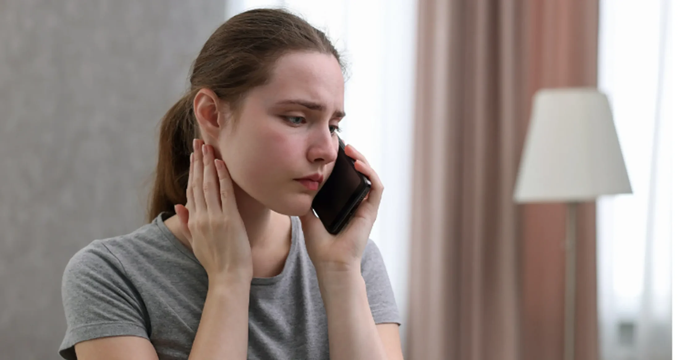A distressed woman makes a phone call to Abuse Counseling & Therapy for support.