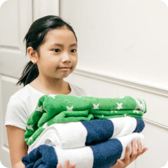 A young girl carries clean blankets at an Abuse Counseling & Therapy shelter.