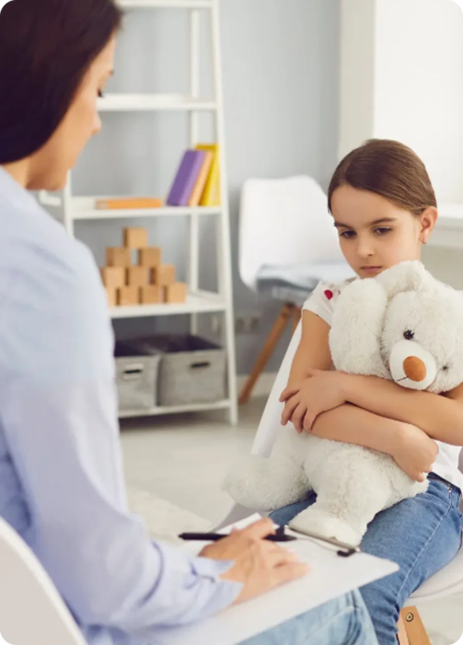 A young girl hugging a teddy bear receives support during an Abuse Counseling & Therapy session.