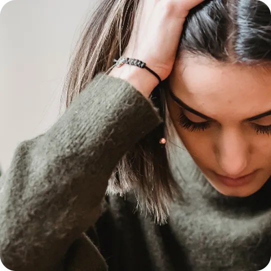 A distressed woman holding her head, symbolizing survivors supported by Abuse Counseling & Therapy.