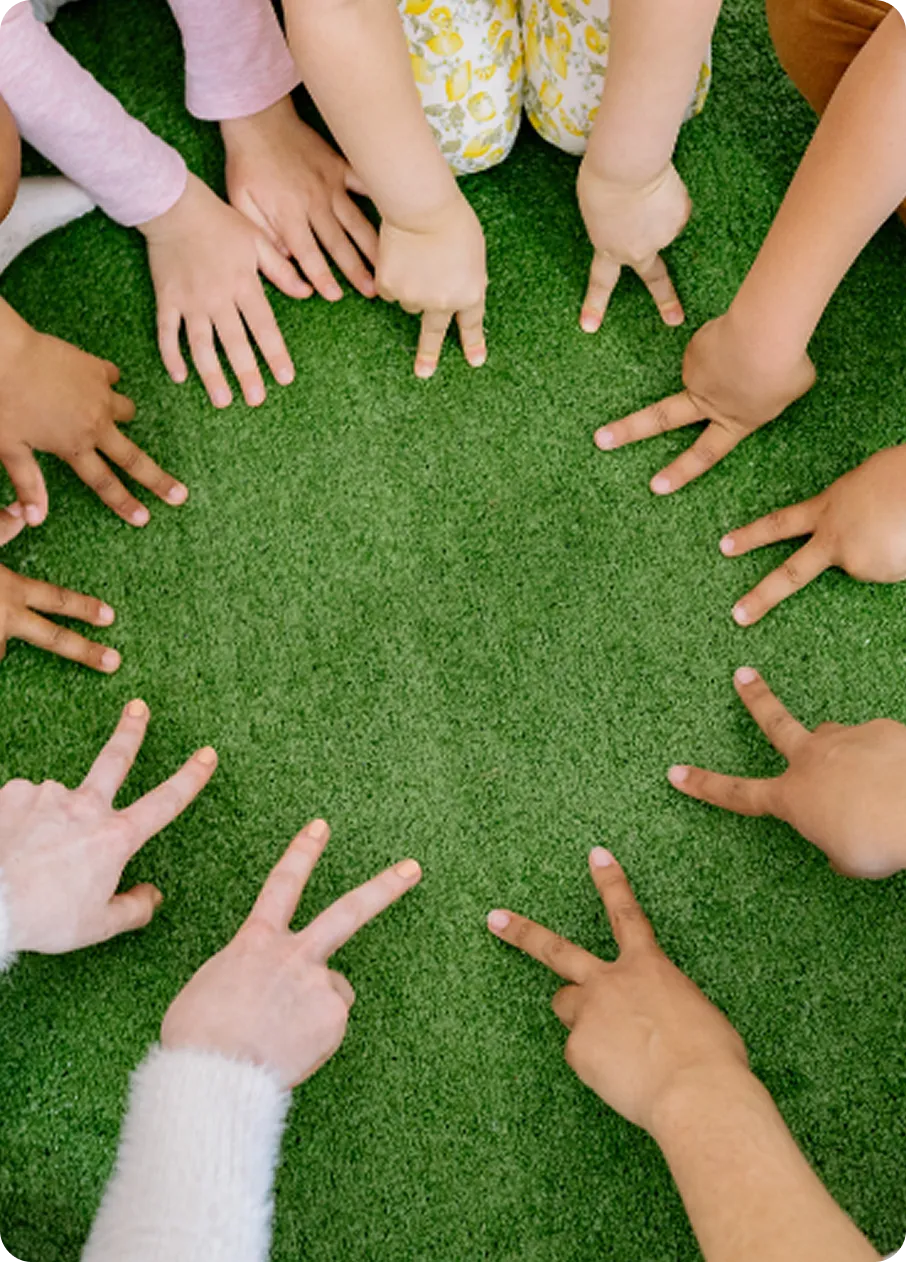 Diverse hands making peace signs in a circle on grass, representing Abuse Counseling & Therapy's support.