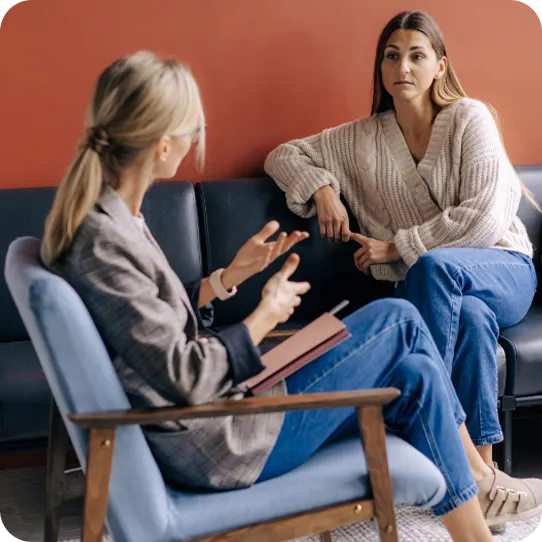 A therapist at Abuse Counseling & Therapy gestures while speaking with a client during a supportive session.