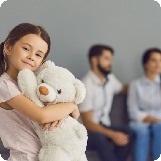A young girl hugs a teddy bear during a family counseling session at Abuse Counseling & Therapy.