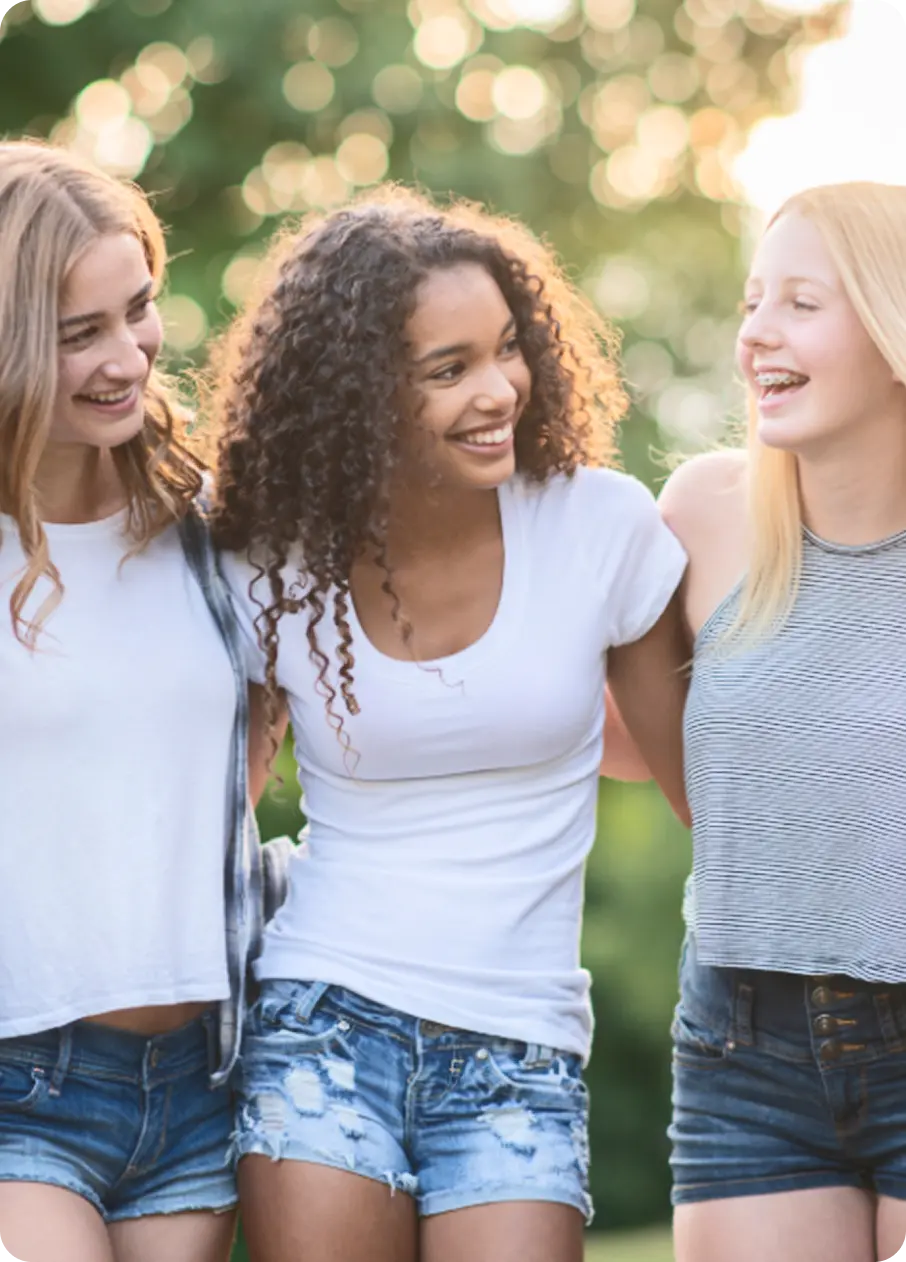 Three smiling teenage girls embrace, supported by Abuse Counseling & Therapy.