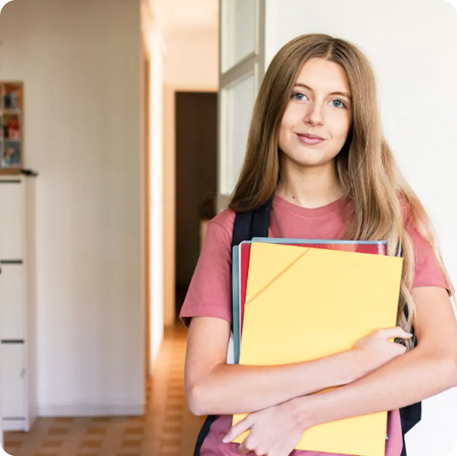 A smiling young student holding folders, representing youth support at Abuse Counseling & Therapy.
