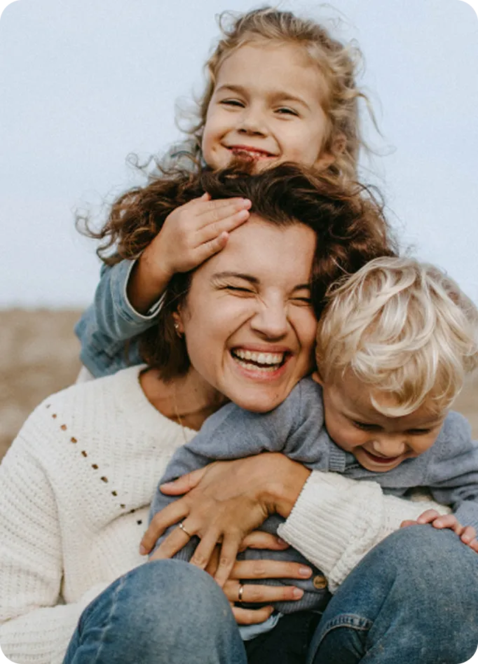 A joyful mother hugs her two young children, representing family healing with Abuse Counseling & Therapy.