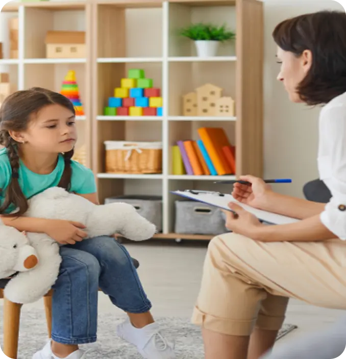 An Abuse Counseling & Therapy specialist conducts a gentle session with a young girl holding a teddy bear.