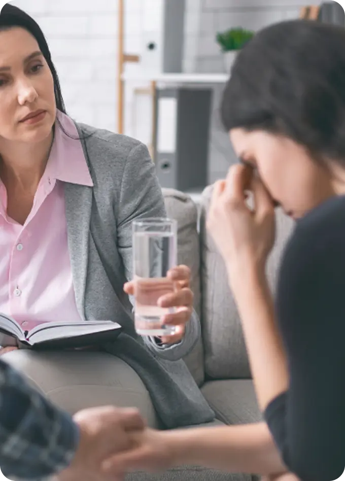 An Abuse Counseling & Therapy counselor offers a glass of water to a distressed client during a session.