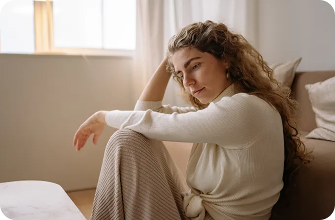 A contemplative woman sits on the floor, symbolizing the healing journey at Abuse Counseling & Therapy.