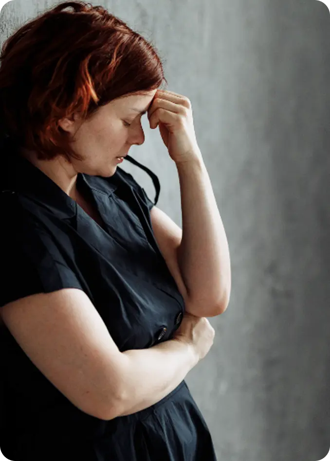 A distressed woman holding her head, representing survivors helped by Abuse Counseling & Therapy.