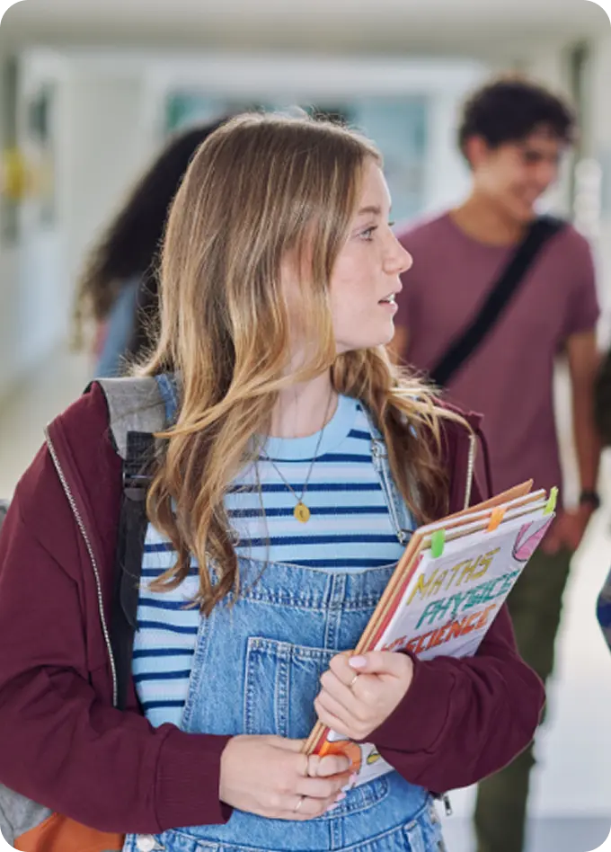 A student holding notebooks in a school hallway, representing youth care by Abuse Counseling & Therapy.