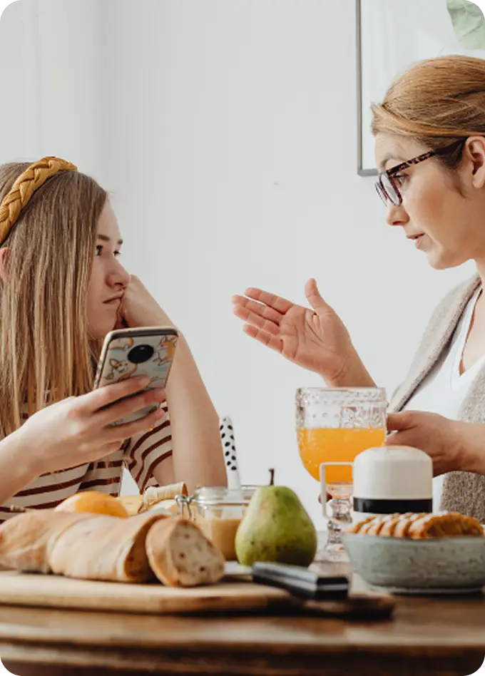 A mother tries to talk to a distracted teen, representing family support from Abuse Counseling & Therapy.