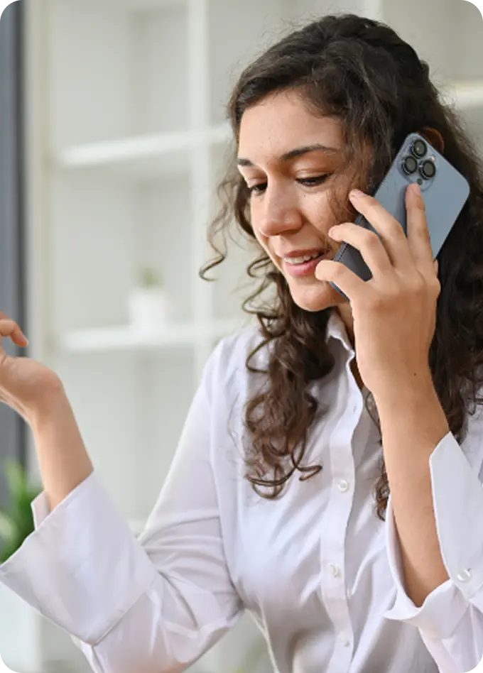 A woman smiles while speaking on her phone, accessing support from Abuse Counseling & Therapy.