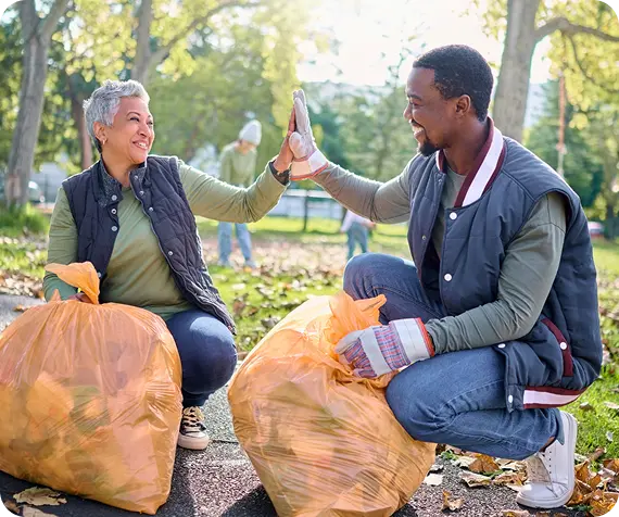 Two volunteers high-five during an Abuse Counseling & Therapy community cleanup.