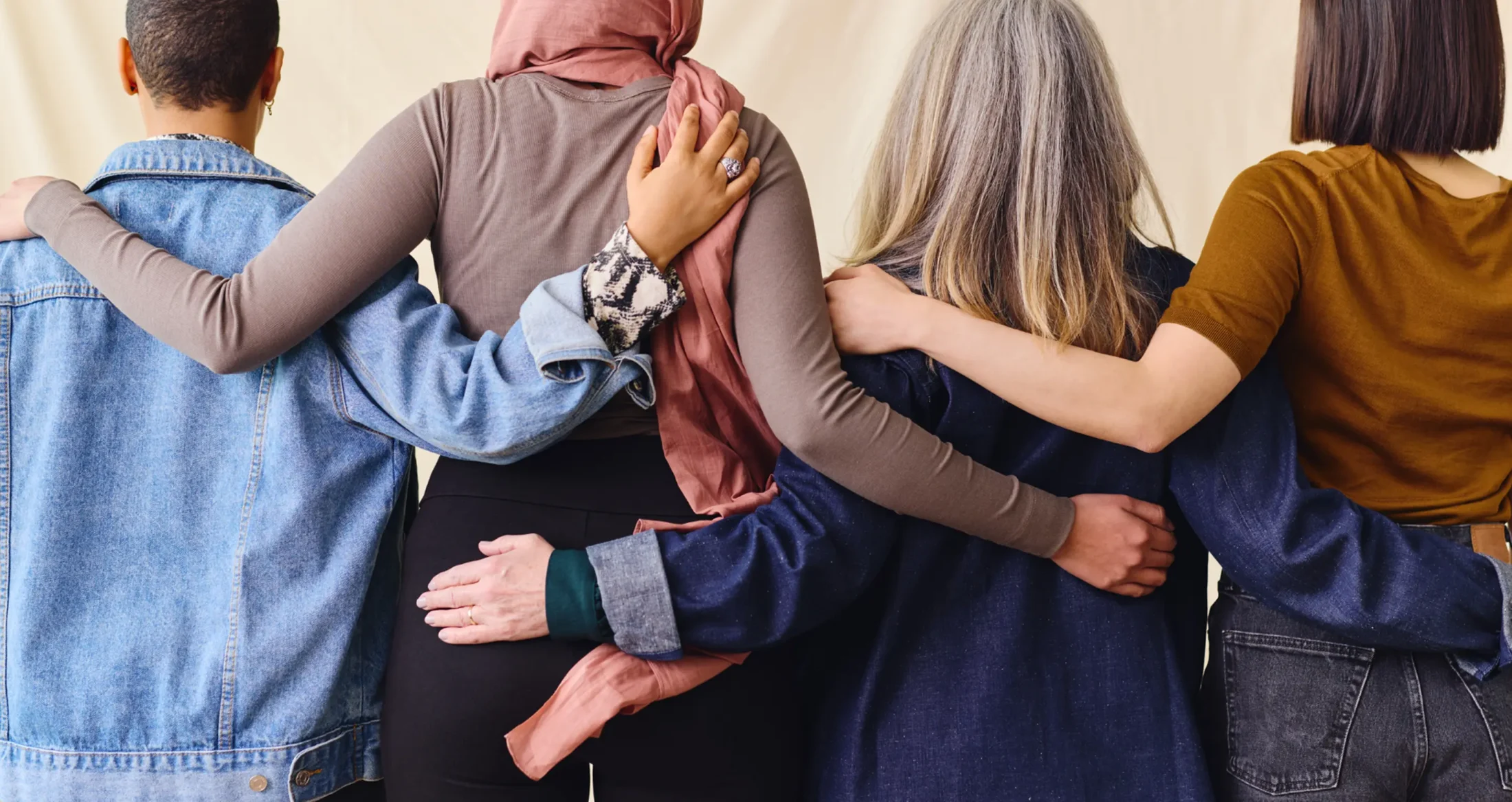 Four diverse women stand arm-in-arm in solidarity, supported by Abuse Counseling & Therapy.