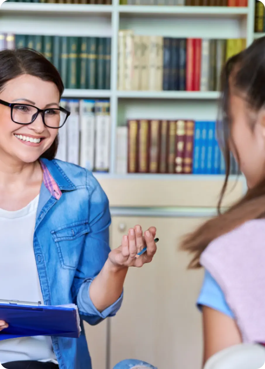 An Abuse Counseling & Therapy counselor smiles warmly while speaking with a young girl.