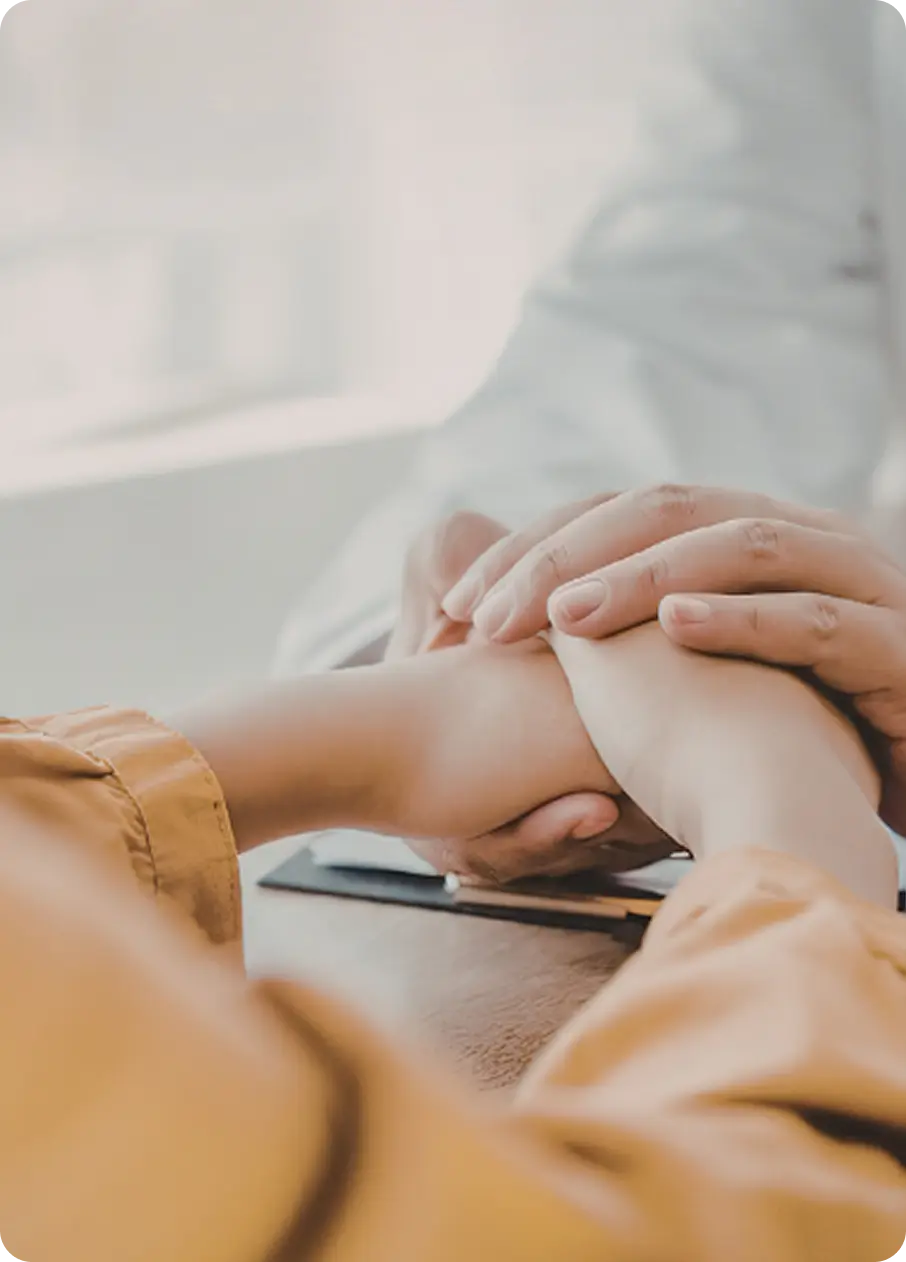 An Abuse Counseling & Therapy counselor supportively holds a client's hands during a session.