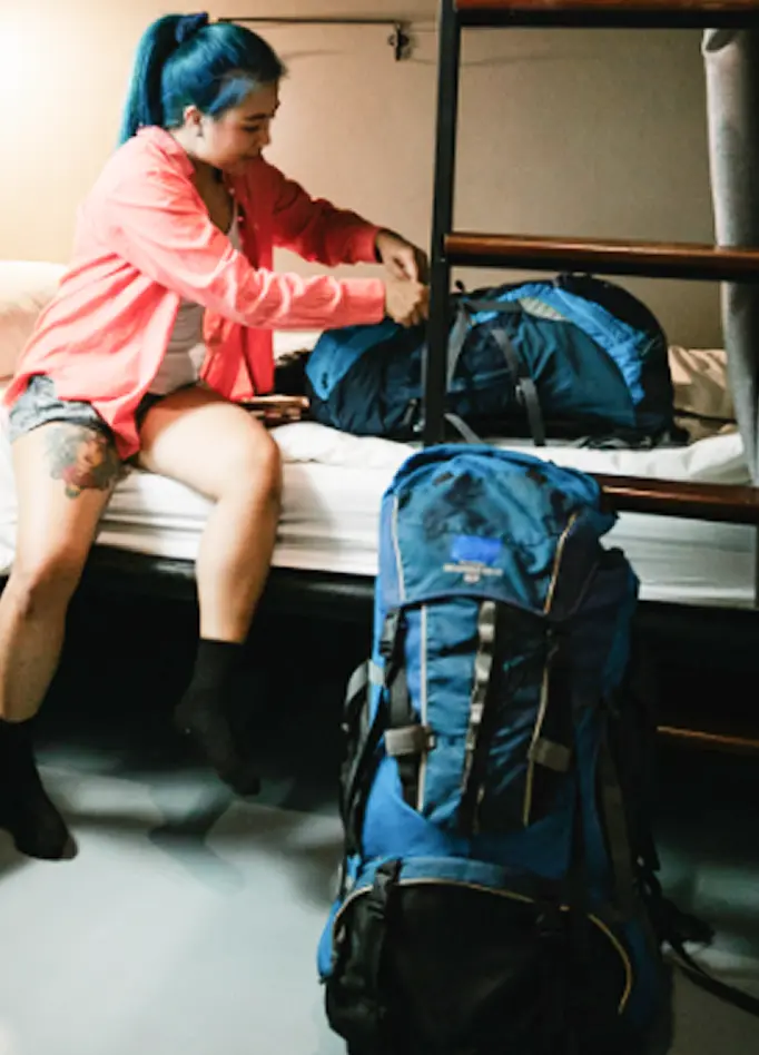 A woman packs her backpack on a bunk bed inside an Abuse Counseling & Therapy shelter.