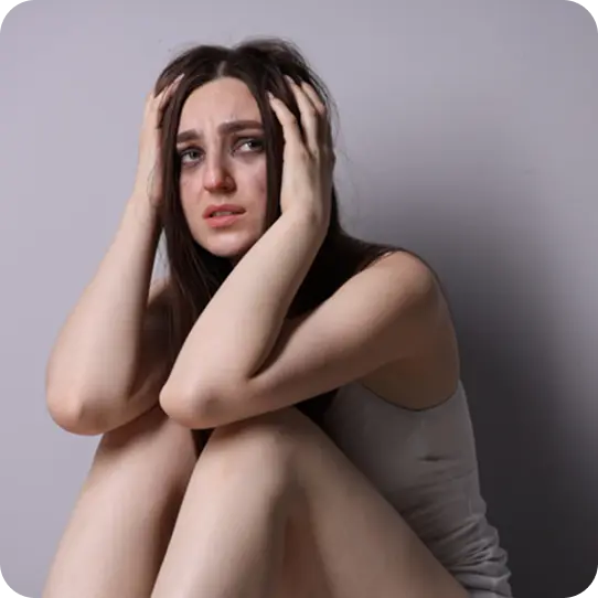 A distressed woman holding her head, representing survivors supported by Abuse Counseling & Therapy.