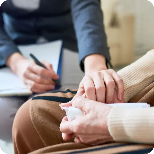 An Abuse Counseling & Therapy counselor gently holds a client's hand during a supportive session.